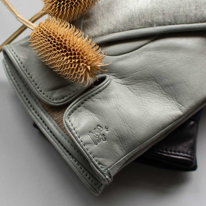 Gray leather glove with a dried teasel head on a light gray background