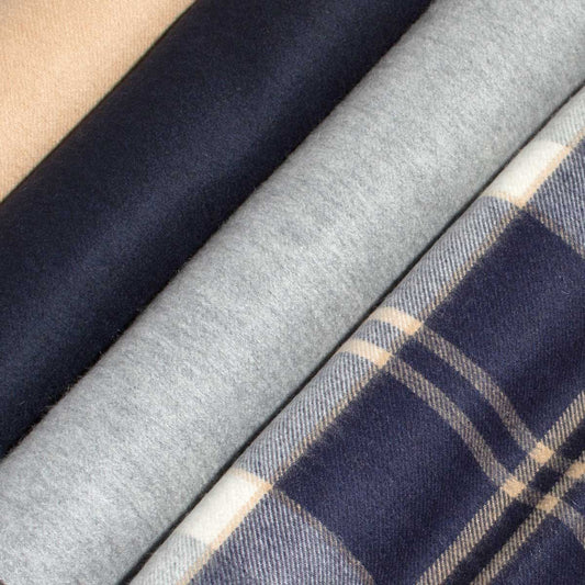 Close-up of four cashmere scarves in tan, navy blue, light grey and checked patterns.